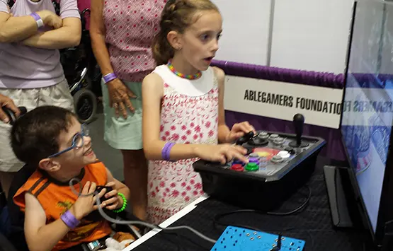 Two kids with disabilities play video games at an AbleGamers Booth