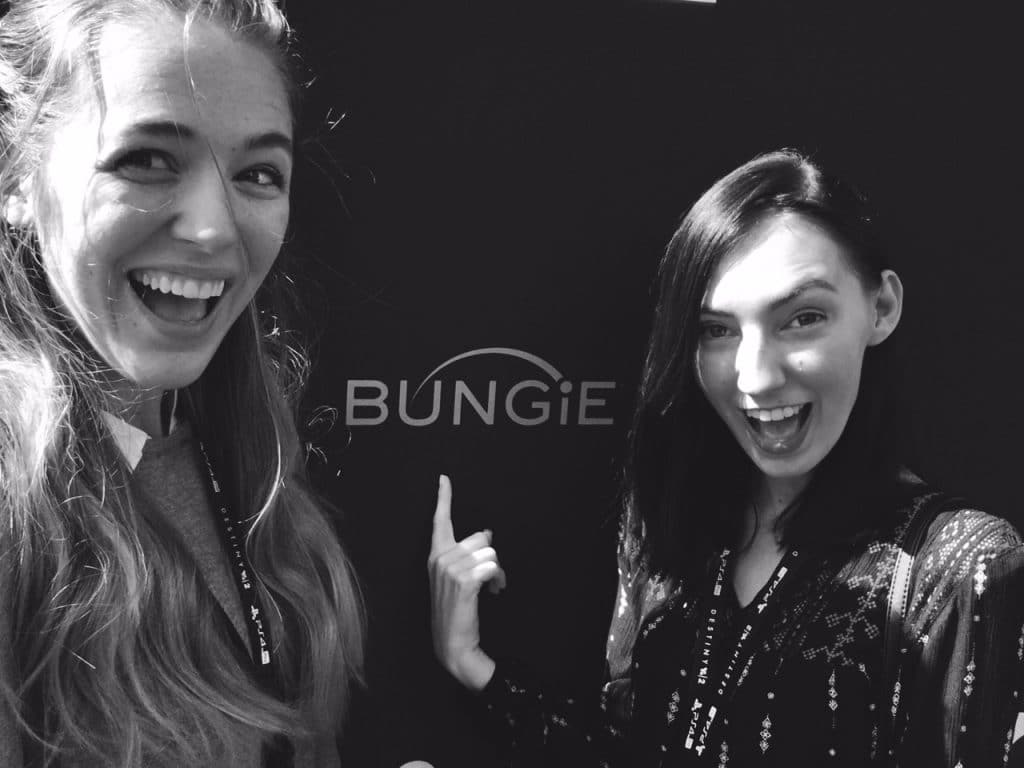 Two women posing in front of the "Bungie" logo.