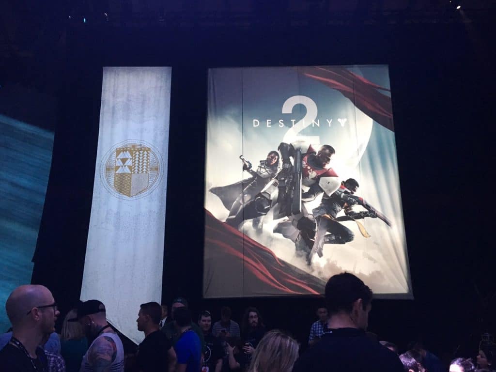 A large banner next to the cover art for Destiny 2, hanging above a crowd of people.
