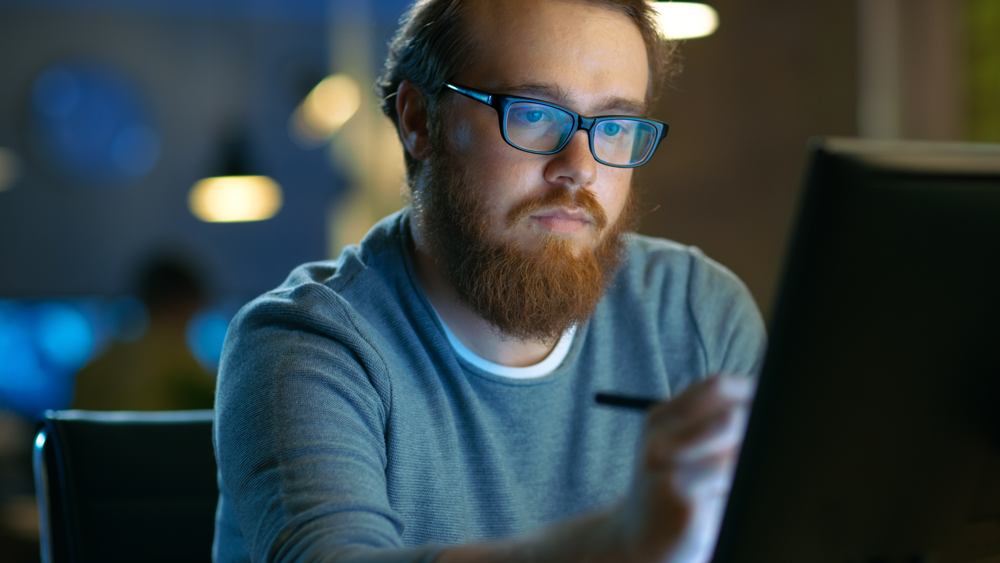 Bearded dude looking at a screen with a pen pointing at it